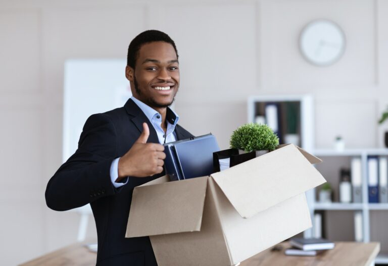Happy black businessman moving office with box and his belongings